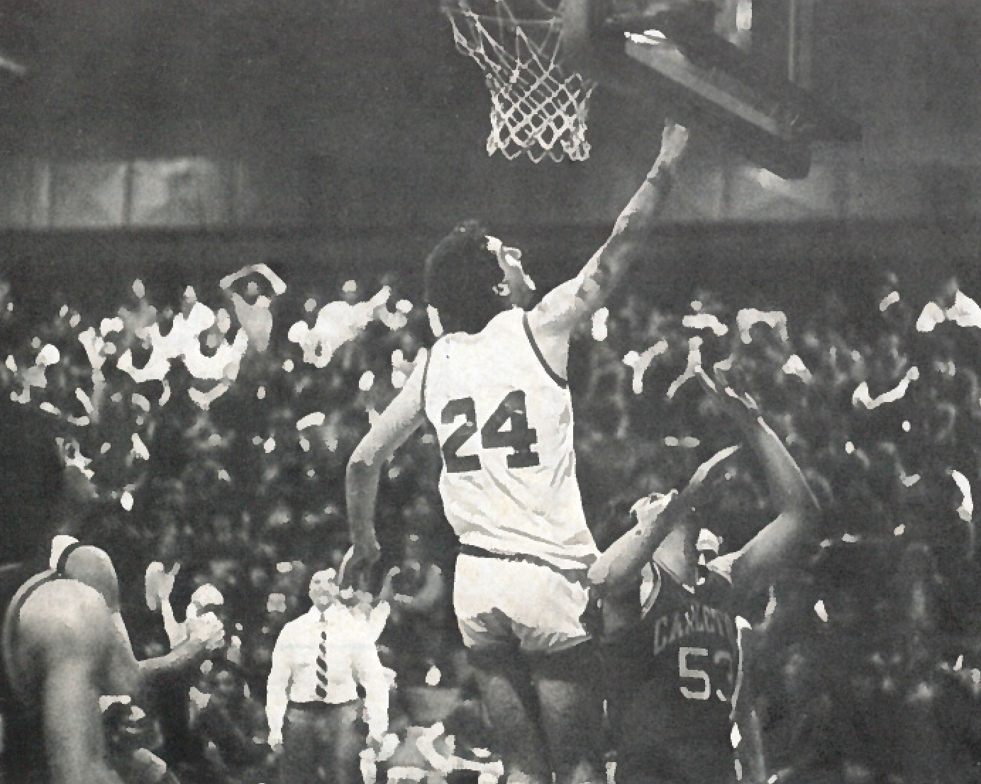 Black and white photo of a basketball player doing a layup in front of a crowd