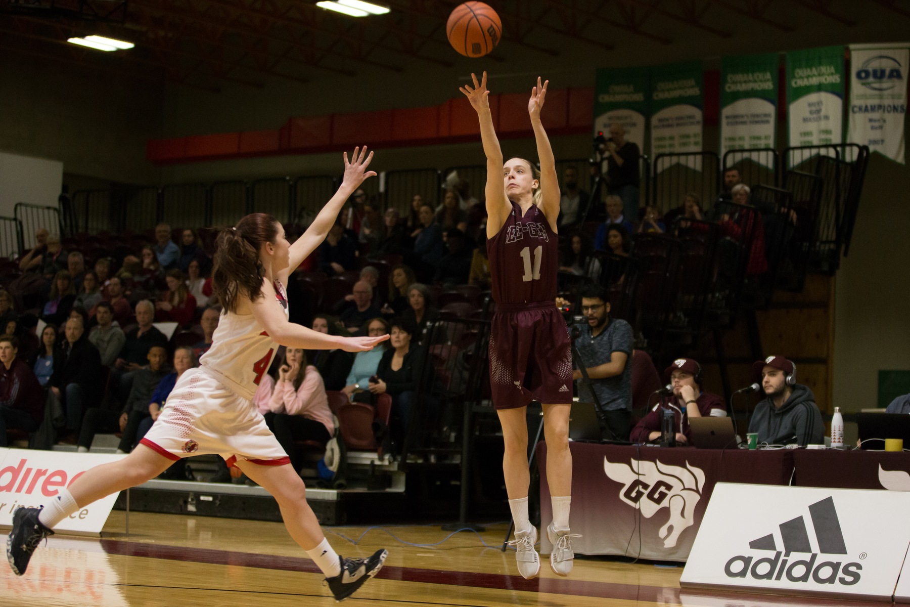 Women's basketball player shoots in front of crowd at Montpetit Hall.