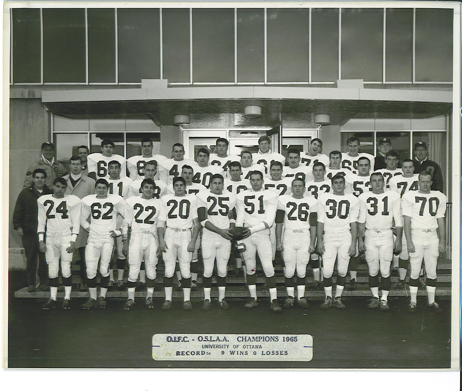 Black and white team photo of football players in four rows. A sticker at the bottom reads: OIFC-OSLAA Champions 1965. University of Ottawa. Record: 9 wins 0 losses.
