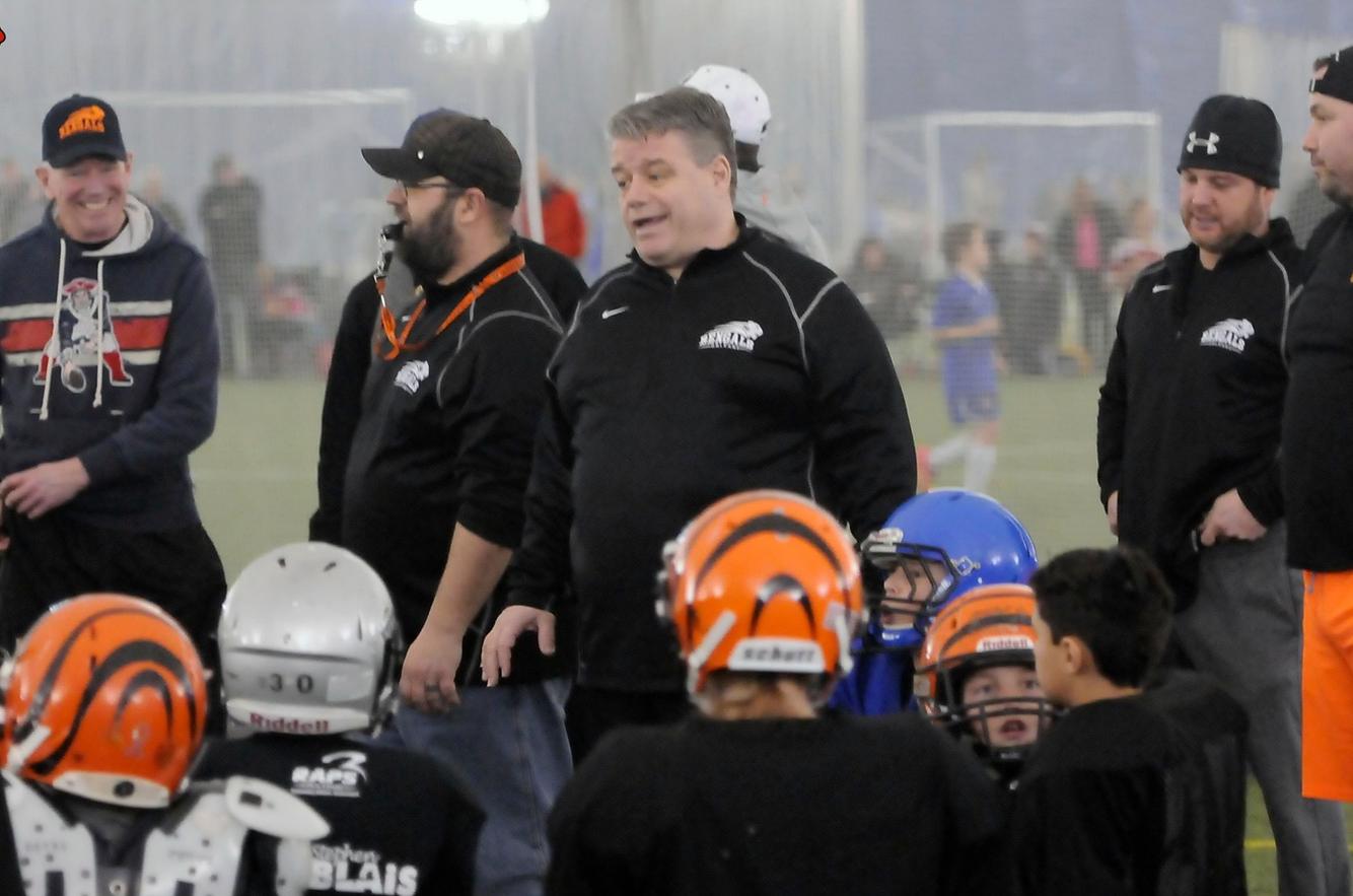 Football coaches with minor players at practice.