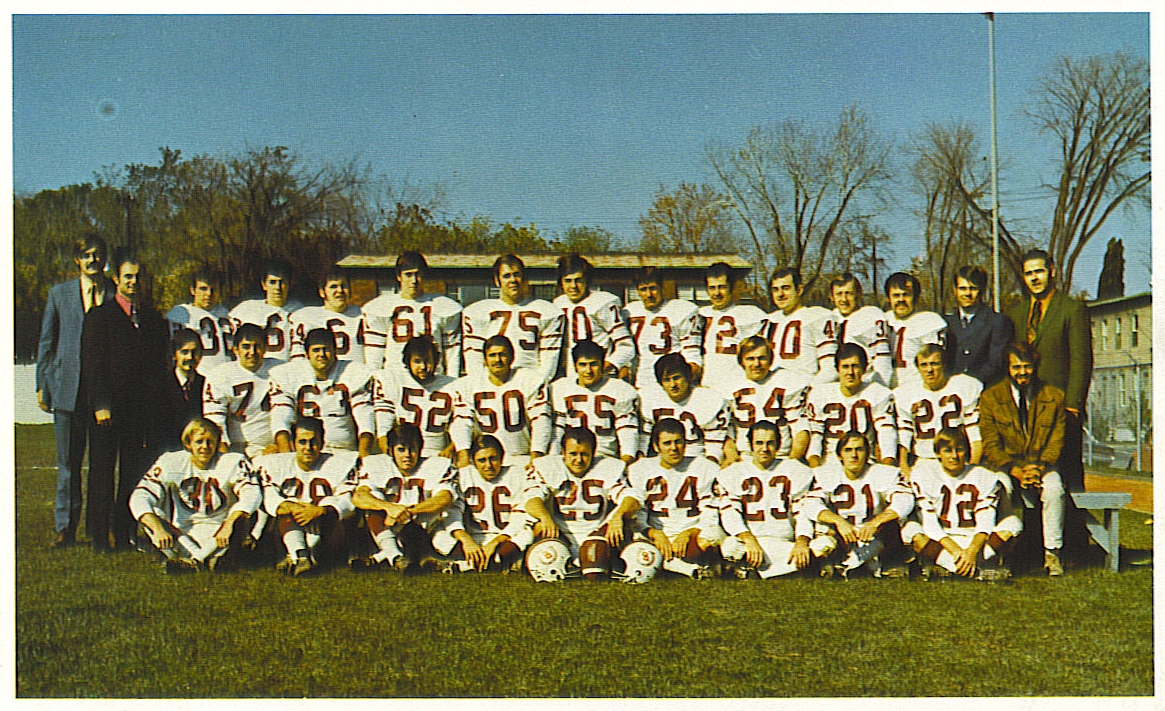 Football players in three rows for team photo with coaches on each end.