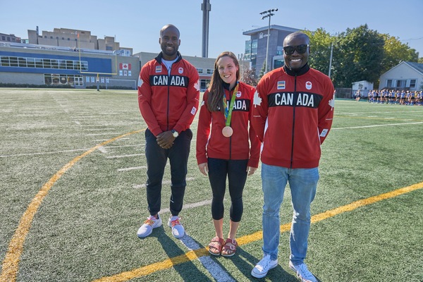 Sekou Kaba, Natasha Watcham-Roy with bronze medal, Segun Makinde in Olympic jackets at Matt Anthony Field