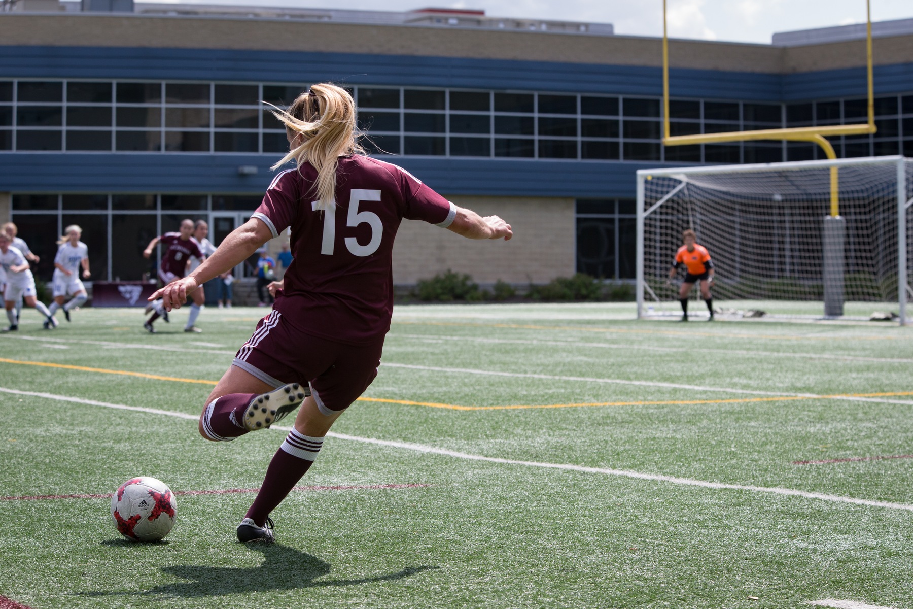 Women's soccer player number 15 seen from back preparing for free kick