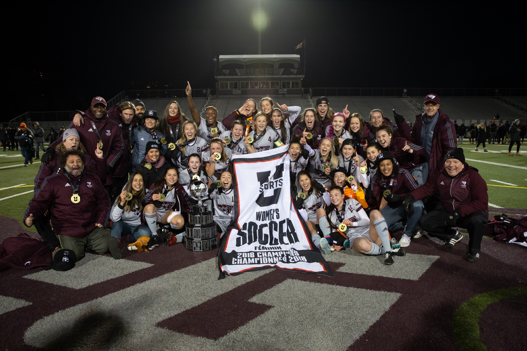 Soccer team group photo on field with U SPORTS championship banner.